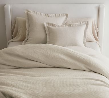 an unmade bed with white linens and pillows