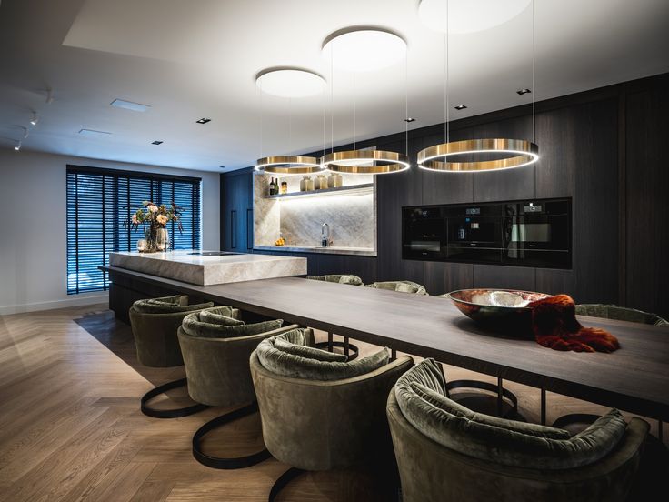 a dining room table with chairs and lights hanging from it's ceiling over the counter