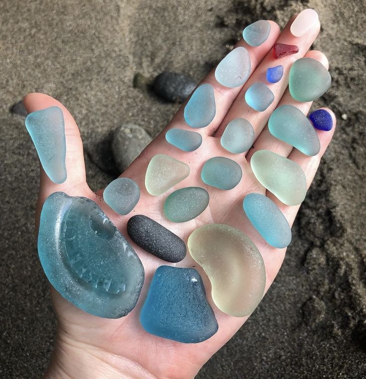 a person's hand holding several sea glass pieces