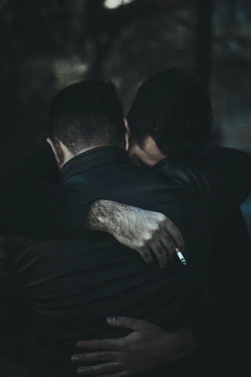 two men hugging each other in the dark