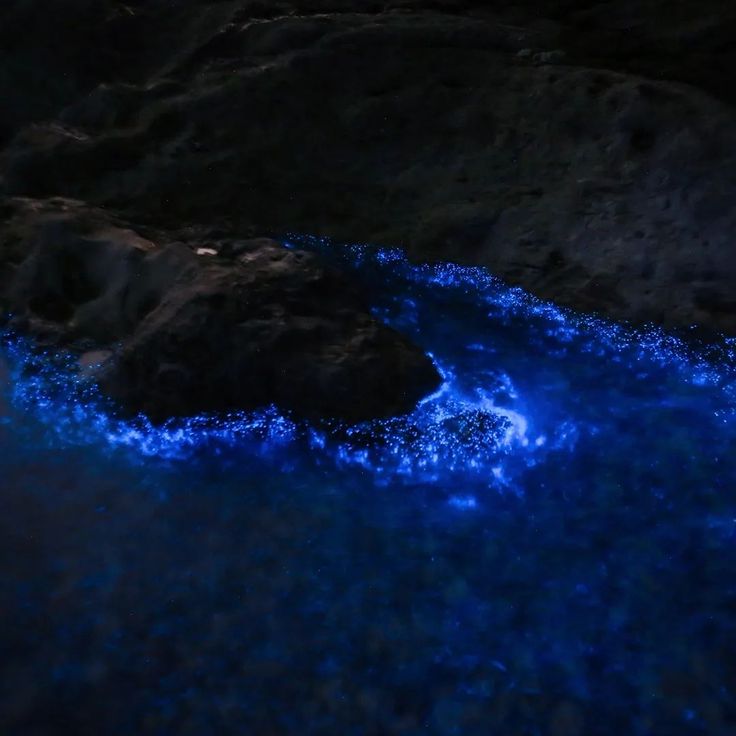 the water is blue and there are rocks in the background with light coming from them