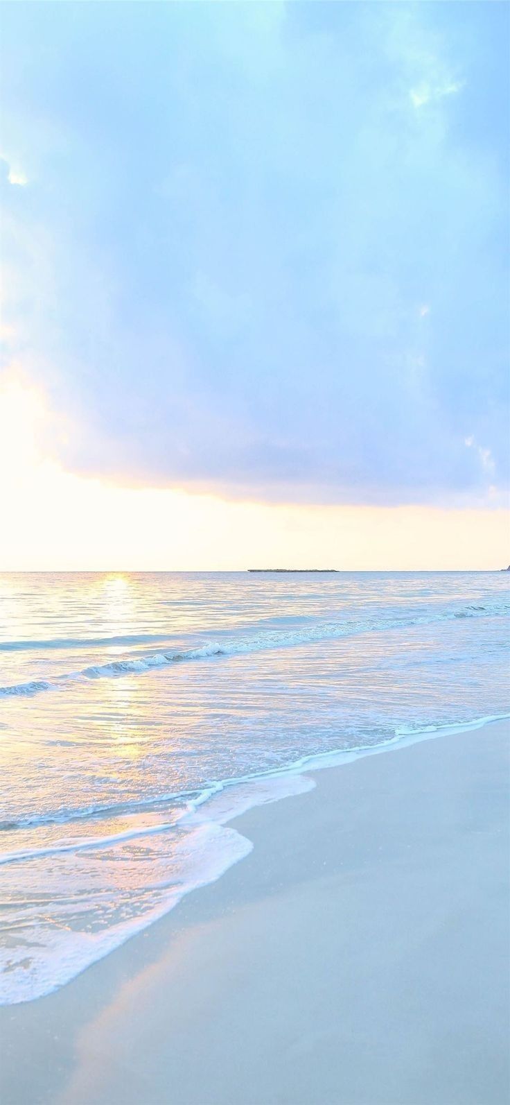 the surfboard is laying on the beach near the water's edge as the sun sets