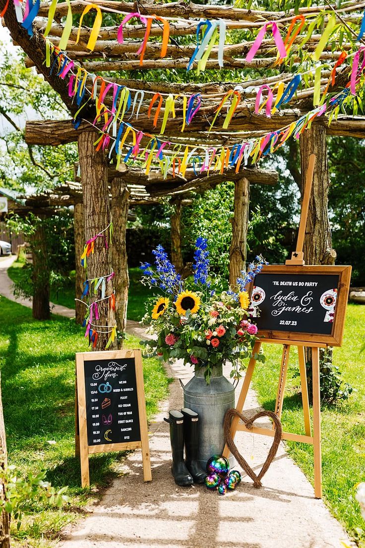 an outdoor ceremony with flowers and streamers on the arborgem, chalkboard menus for guests to sign