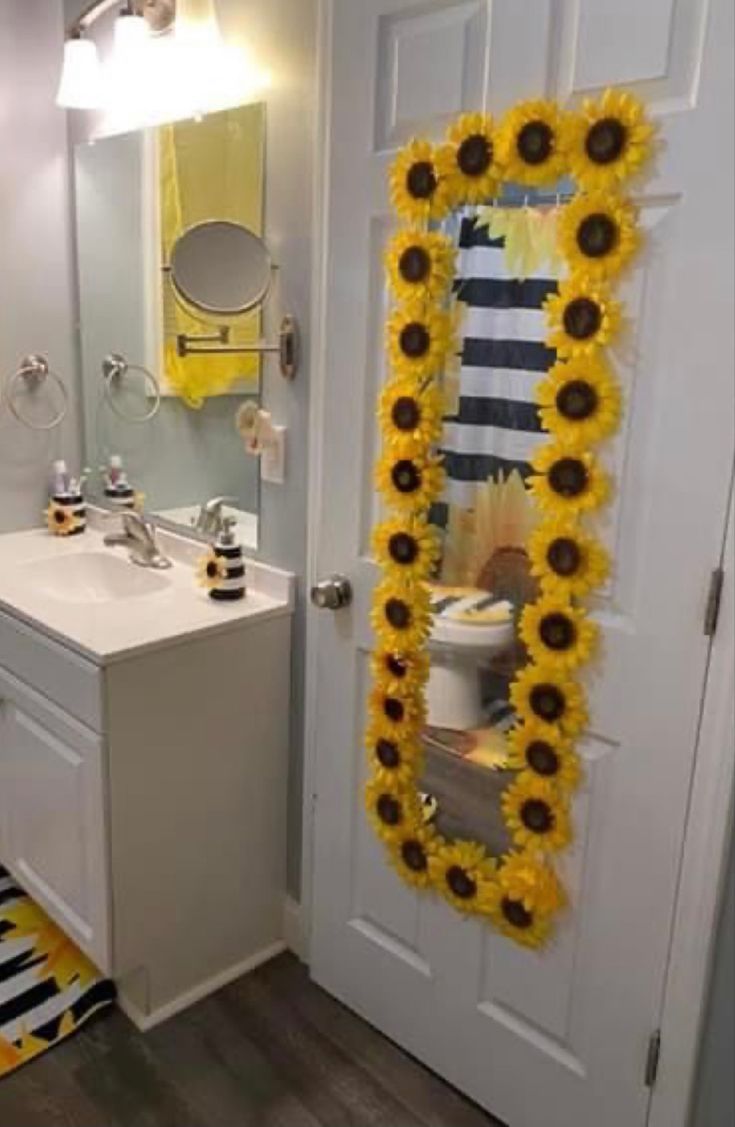 a bathroom with sunflower decorations on the door and mirror above the sink in front of it