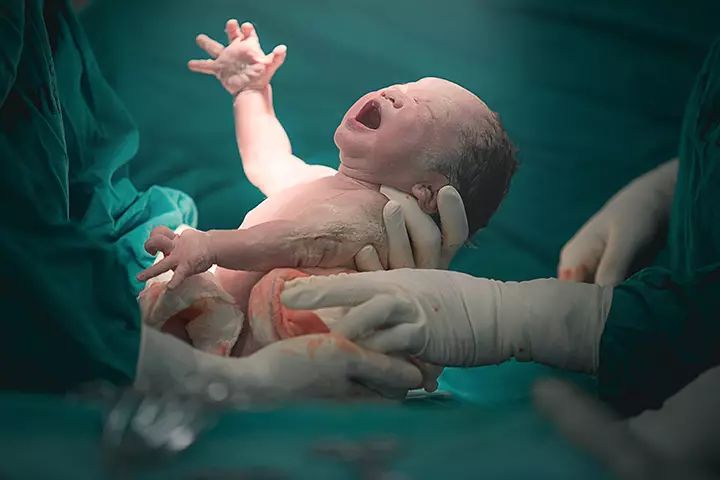 a baby is being held in an inclosure by medical staff and nurse's hands