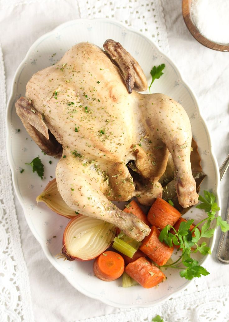 a whole chicken on a plate with carrots and celery