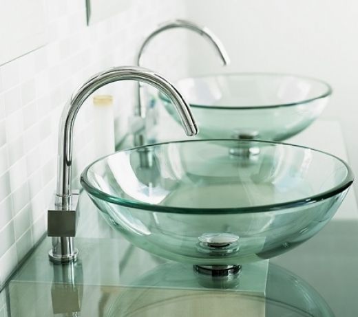 two glass bowls are sitting on the counter in front of a mirror and faucet