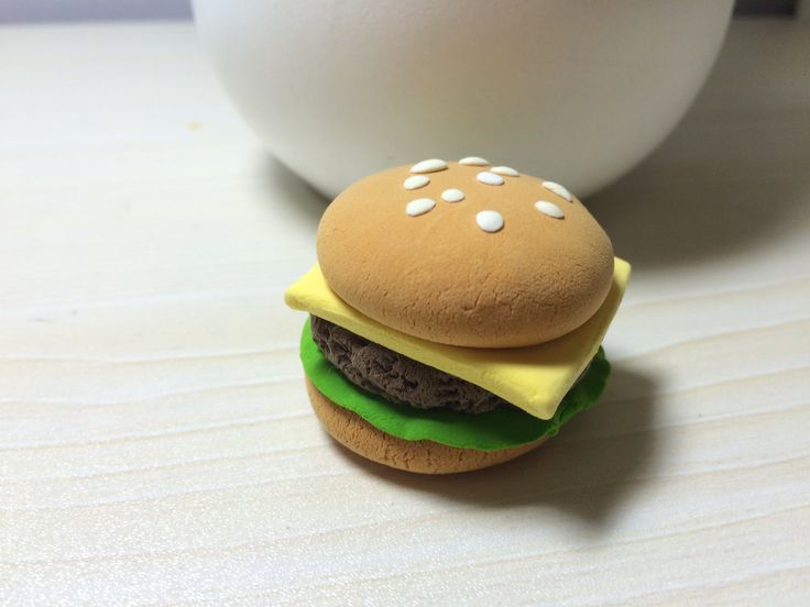 a toy hamburger with cheese on it sitting next to a white egg in the background