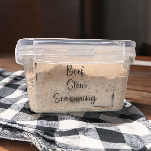 a plastic container filled with seasoning sitting on top of a table next to a black and white checkered cloth