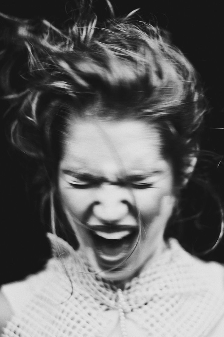 a black and white photo of a woman with her hair in the air, screaming