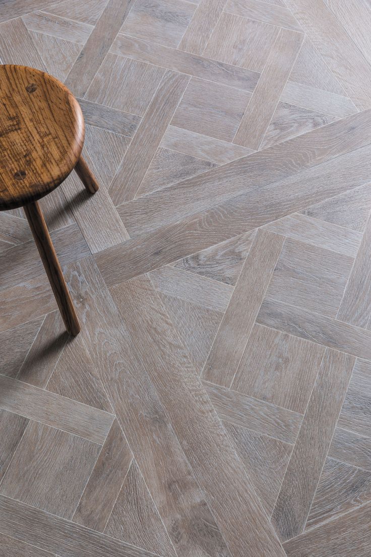 a small wooden table sitting on top of a floor next to a white tiled wall