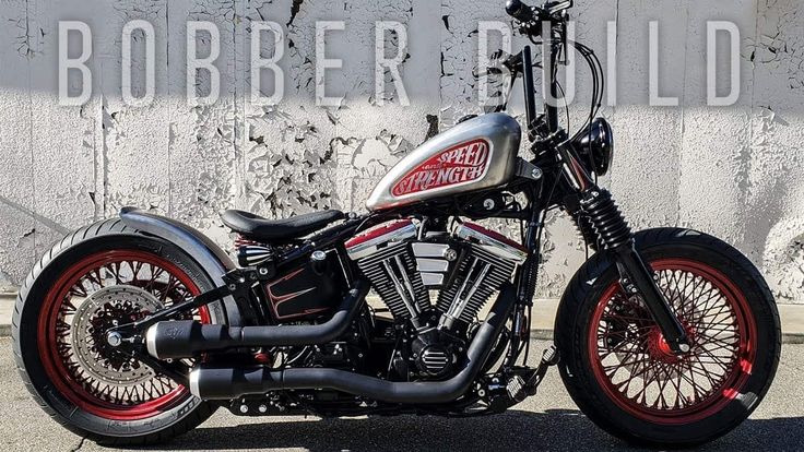 a black and red motorcycle parked in front of a wall with the words bobber build on it