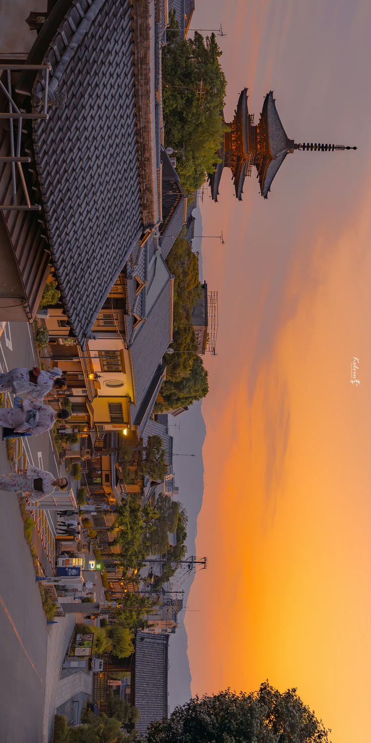 the sun is setting behind some buildings and trees