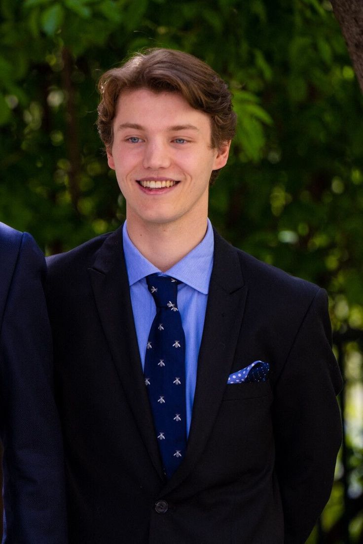 two young men wearing suits and smiling for the camera