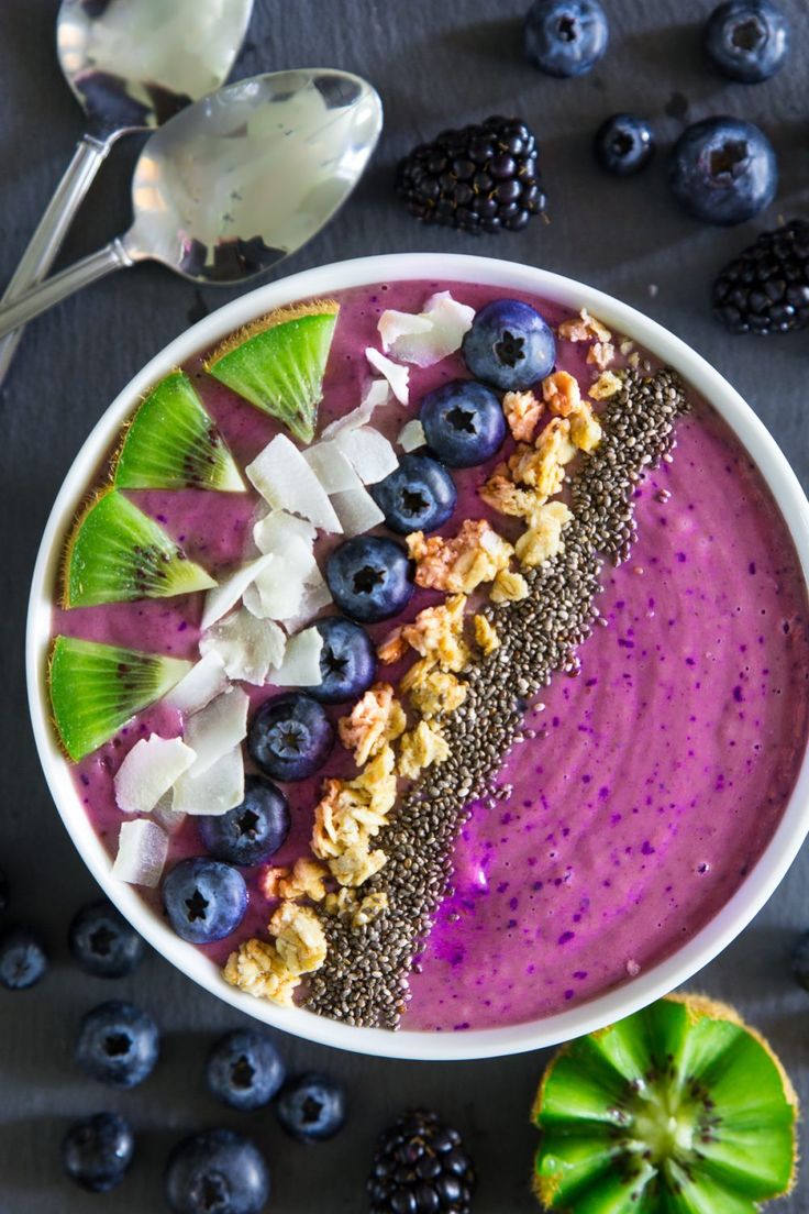 a bowl filled with blueberry smoothie and topped with granola crumbs