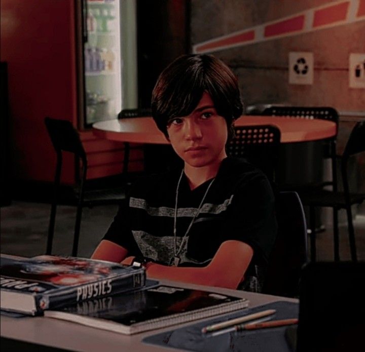 a young boy sitting at a table with books