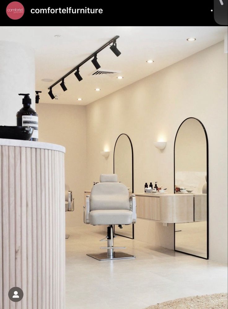 a white chair in a room with mirrors and lights on the wall behind it is a hair dryer