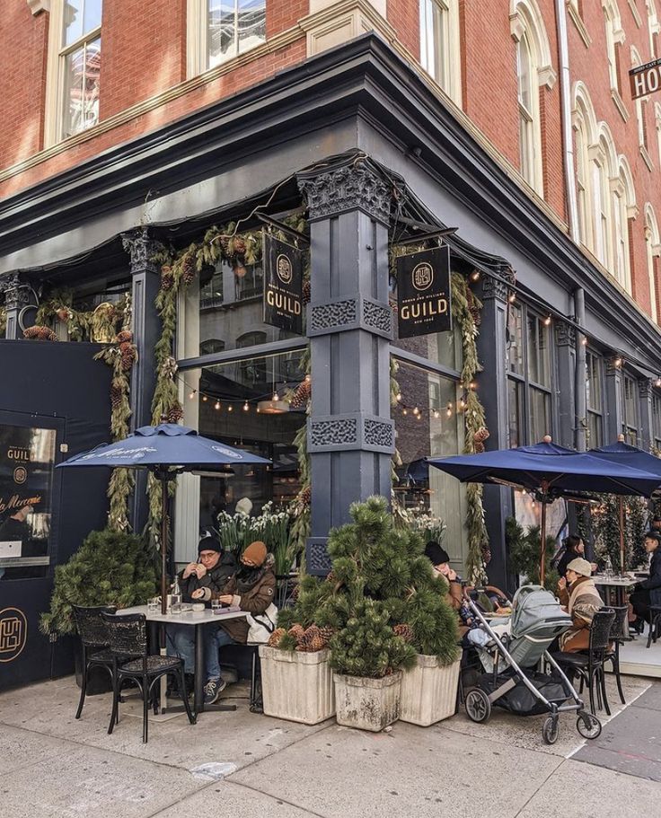 people sitting at tables in front of a restaurant