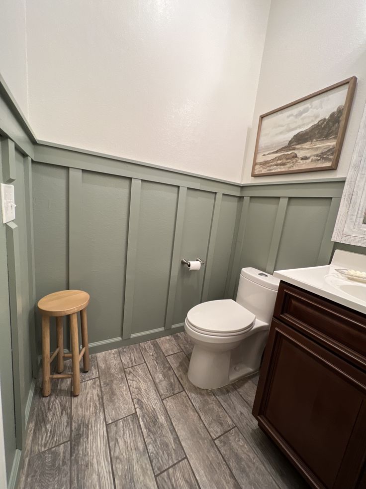 a white toilet sitting in a bathroom next to a wooden counter and vanity with a stool