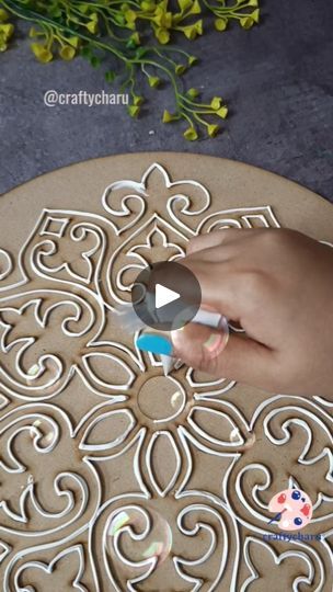 a person is using a marker to decorate a decorative design on a round surface with flowers in the background