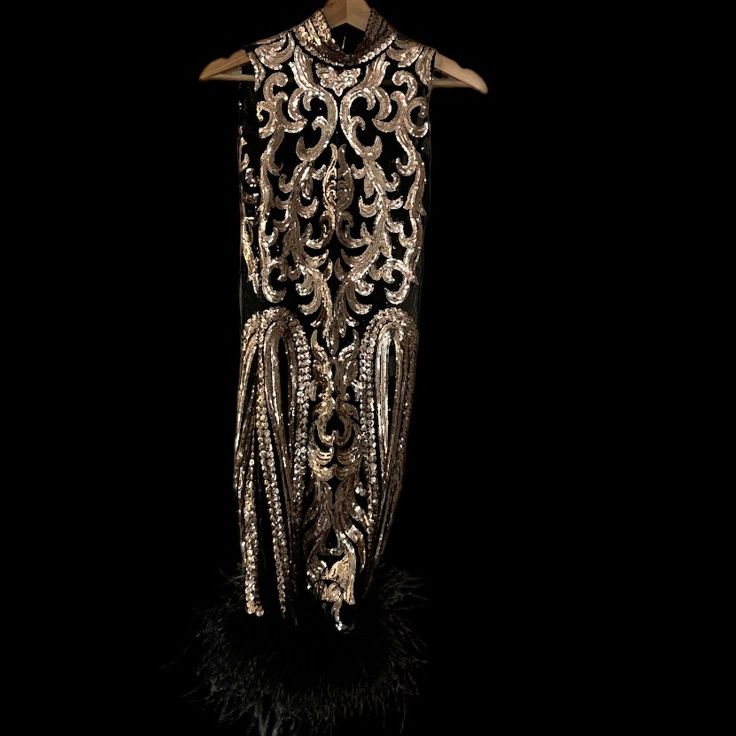 a mannequin is adorned with beads and feathers on a black background in the dark