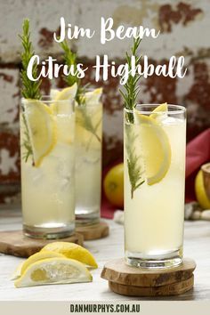 two glasses filled with lemonade and rosemary garnish next to sliced lemons