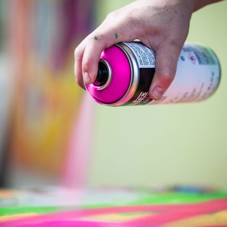 a person holding a spray bottle and spraying it on top of a colorful table cloth