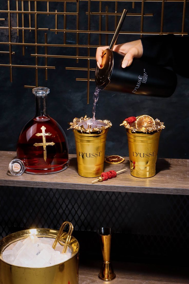 a person pouring wine into two gold buckets