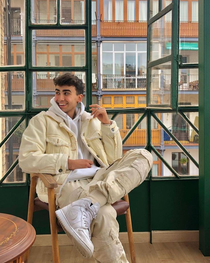 a man sitting in a chair talking on a cell phone and smiling at the camera