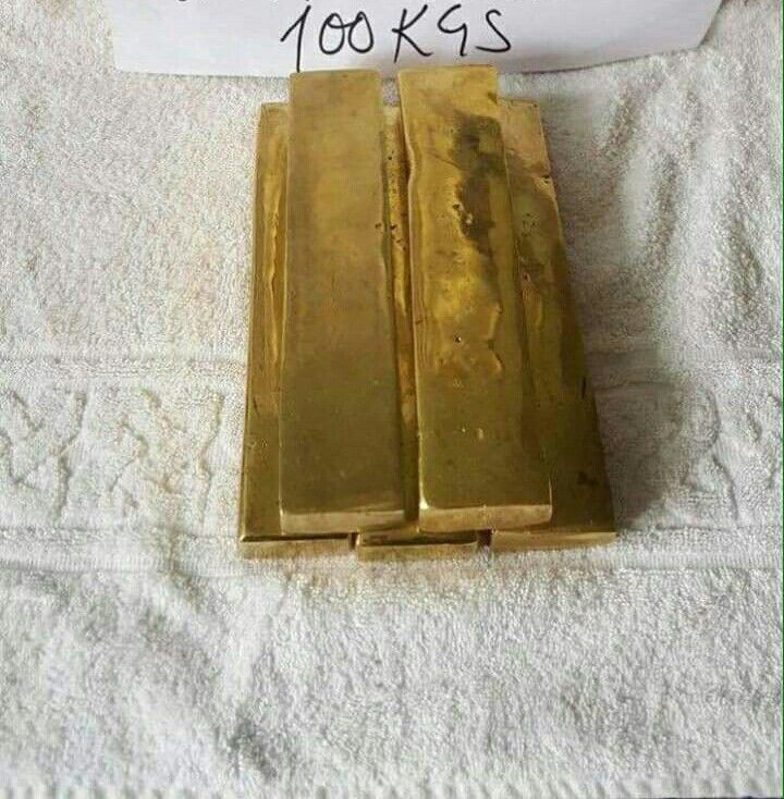 two gold bars sitting on top of a towel next to a sign that says, $ 100k is