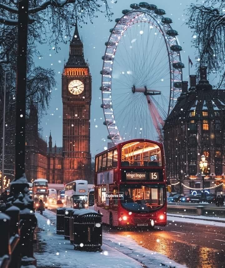 a red double decker bus driving down a snow covered street next to a clock tower