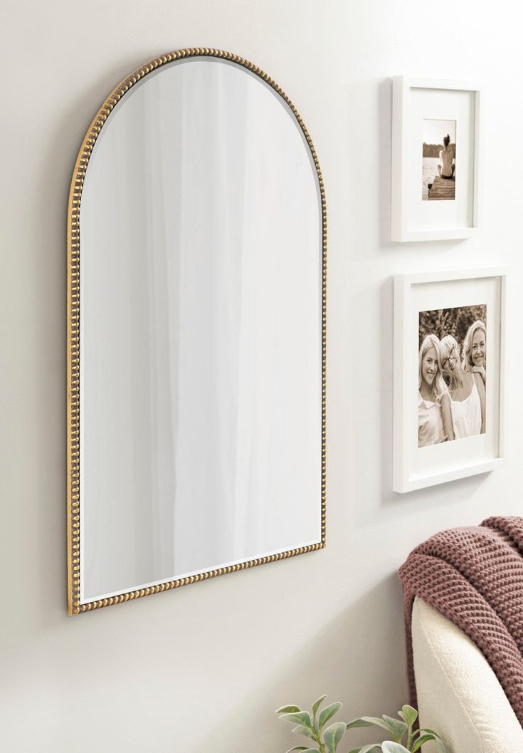 a mirror hanging on the wall next to a chair and potted plant in front of it