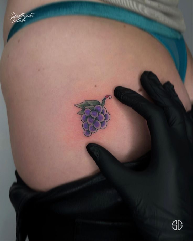 a woman with a tattoo on her stomach has grapes tattooed on the side of her belly