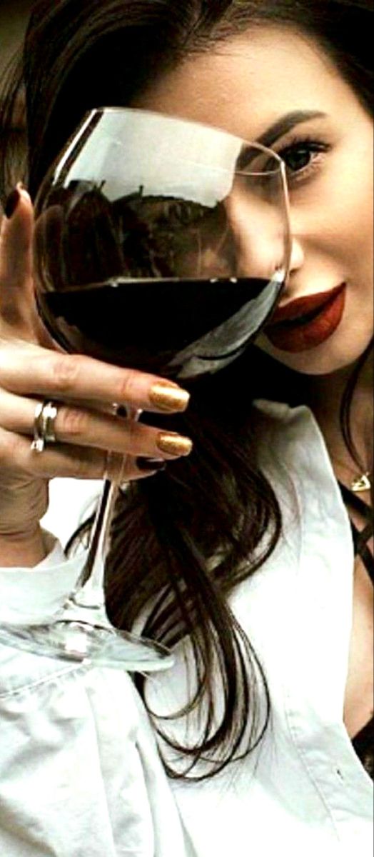 a woman is holding a glass of wine