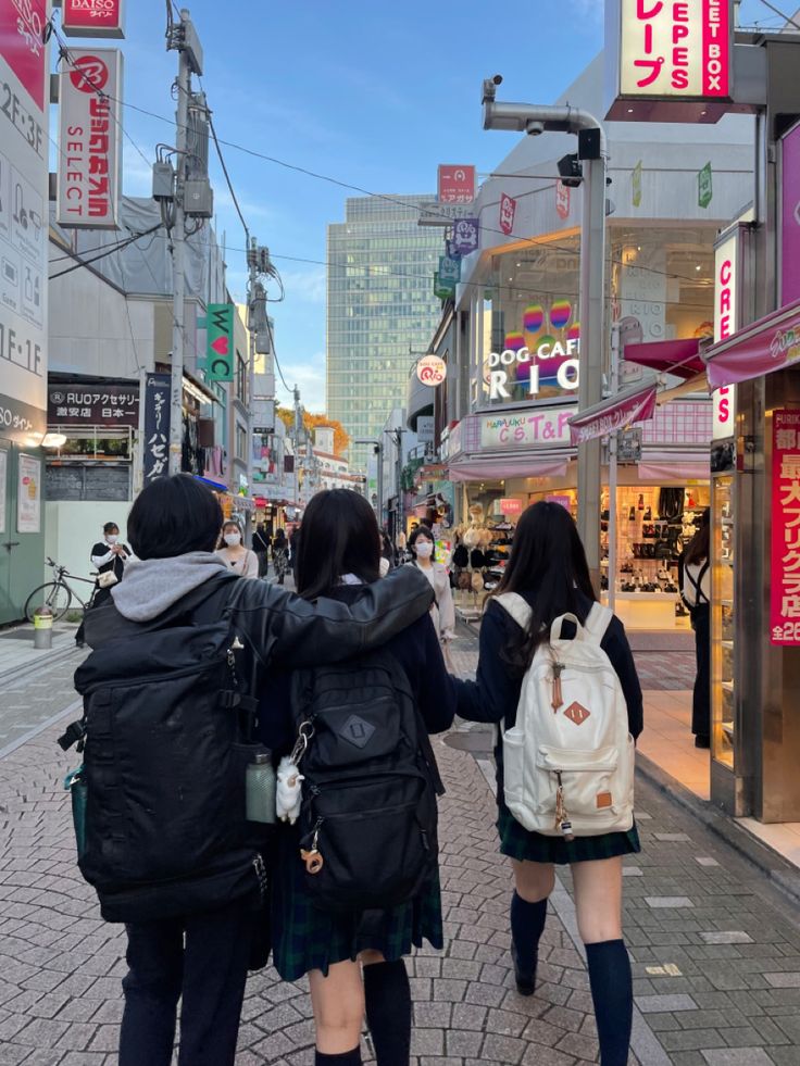 two girls are walking down the street with backpacks on their back and one girl is holding her hand