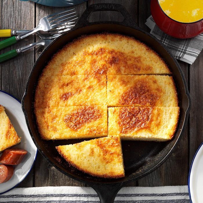 a skillet with some food in it on a wooden table next to plates and utensils