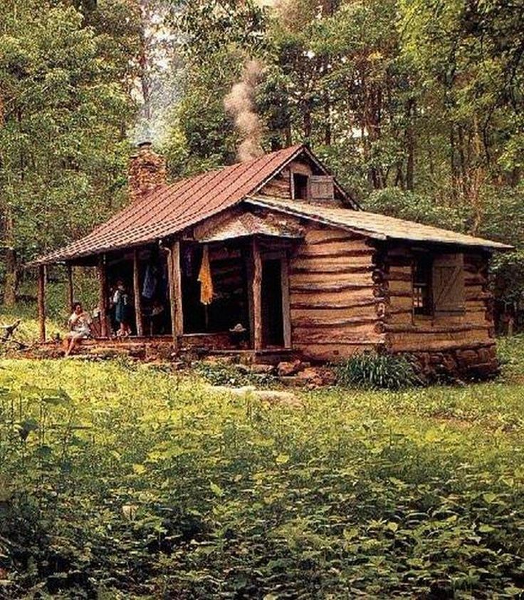 an old log cabin in the woods with people standing on it's front porch