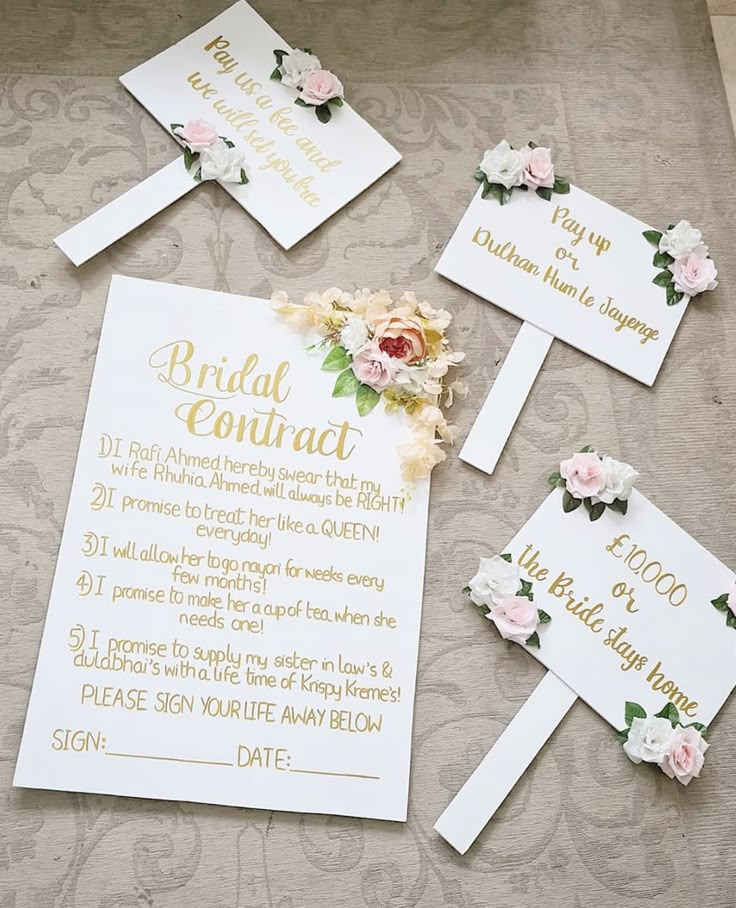 the wedding stationery is laid out on the floor with flowers and gold foil lettering