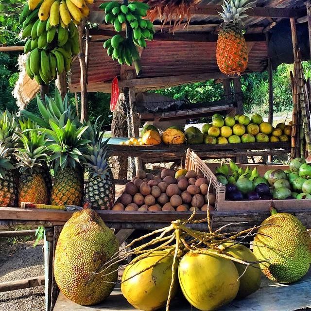 there are many different fruits on display at the market stall with bananas, pineapples, and other fruit