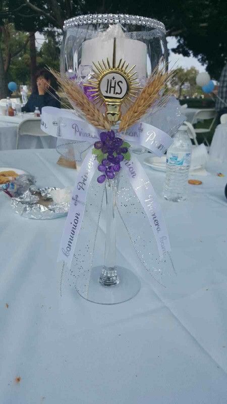 a wine glass decorated with wheat and purple flowers on a white table cloth at an outdoor event