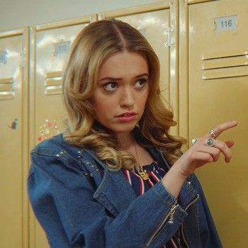 a woman pointing at the camera in front of lockers with her finger on it