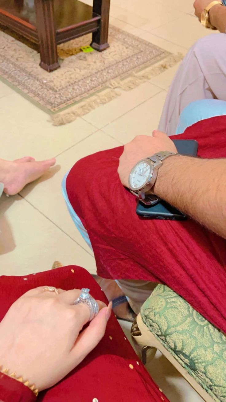 two people sitting on the floor with their feet up and one person holding a watch