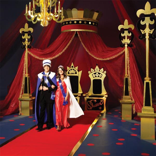 two people standing on a red carpet in front of a stage with gold chandeliers