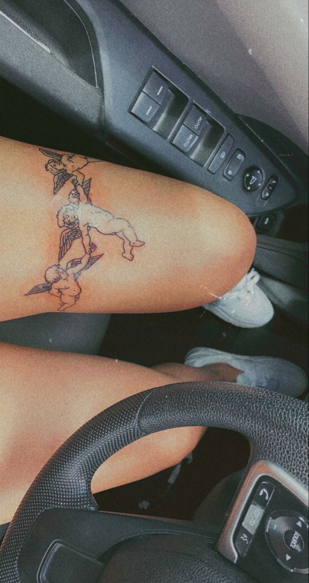 a woman with a tattoo on her arm sitting in a car next to a steering wheel