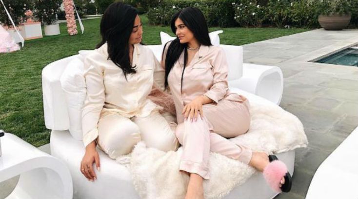 two women sitting on top of a white couch