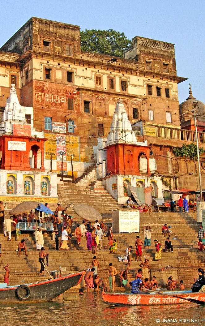 many people are standing on the steps near some buildings and boats in the water,