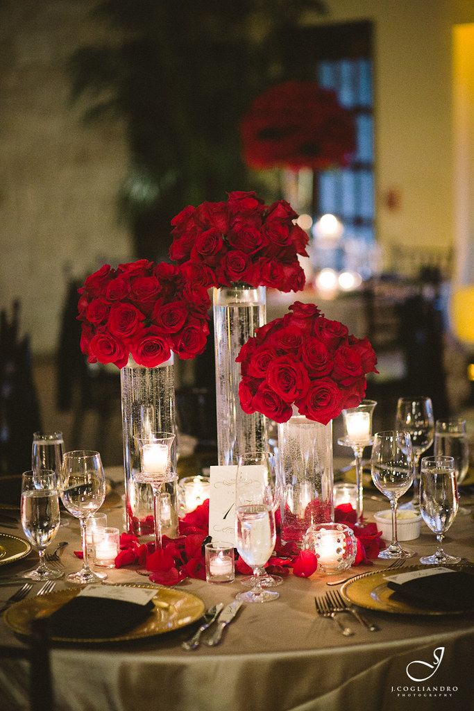 the centerpieces are filled with red roses and candles