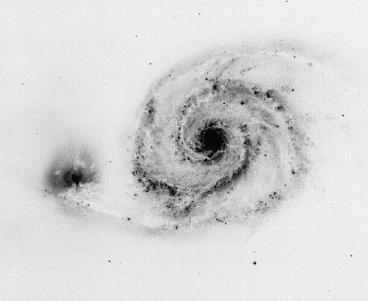 a black and white photo of a spiral in the sky, with dust swirling around it