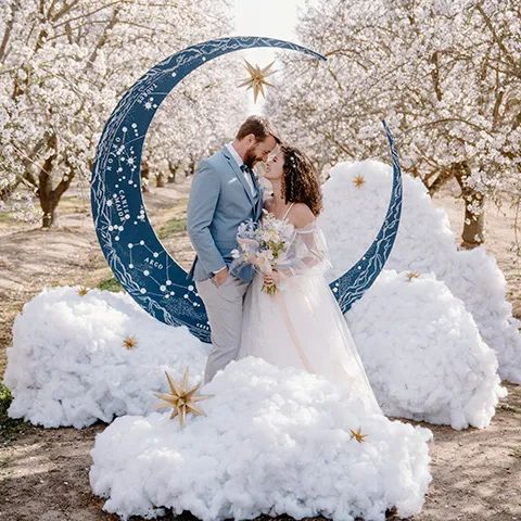 a bride and groom standing in front of a moon sculpture