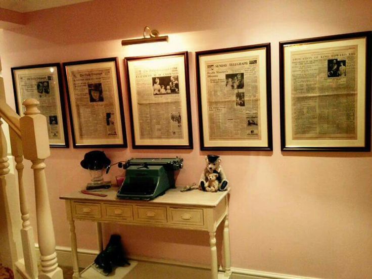 an old typewriter on a desk in front of three framed newspaper pages